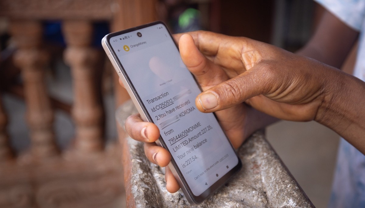 Close-up of a person checking their mobile money account balance after receiving a transaction notification.