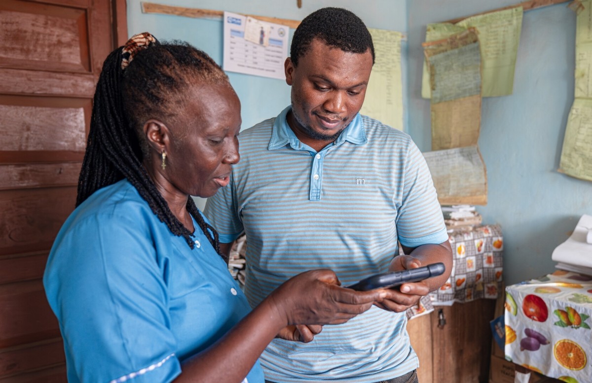 A head teacher and CGA staff member focus on a tablet screen.